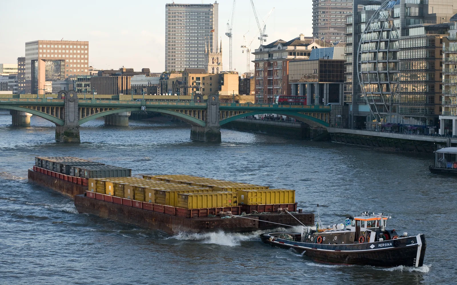 Barges towed by tugboat on river waterway, industrial river transportation